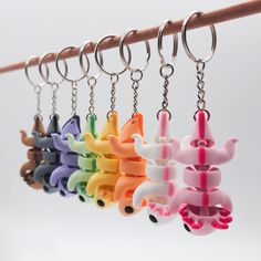 a row of key chains hanging from a wooden pole with different colored plastic animals on them