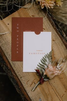 an image of wedding stationery with flowers on the wood planks and greenery