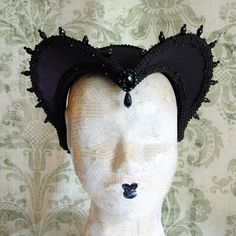 This is a purple and black version of one of most successful designs called Countess. This vampire style headdress is covered with dark purple taffeta and embellished with black cord trimming all around the edges.It is further trimmed with black crystal details that create a halo effect as well as small l beads that were hand-sewn on the trimming to create rich textural interest. The piece is completed with a black crystal handmade element placed at the center front for all that extra drama that Black Fitted Gothic Costume, Fitted Black Gothic Costume, Black Medieval Costume Accessories For Cosplay, Medieval Black Costume Accessories For Cosplay, Gothic Costume Accessories For Masquerade And Cosplay Events, Fitted Cat Ears Halloween Costume Accessories, Handmade Black Headpiece For Costume, Fitted Halloween Costume Accessories With Cat Ears, Punk Style Black Costume For Festival