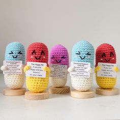 four crocheted eggs with faces and words on them sitting in front of each other