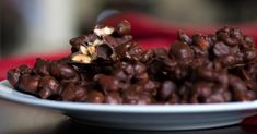 a white plate topped with lots of chocolate covered food next to a red table cloth