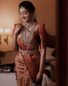 a woman in an orange sari is smiling and looking at her jewelry on the neck