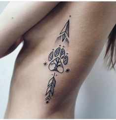 a woman's stomach with an arrow and dog paw tattoo on the left side