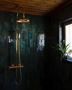 a bathroom with green tiles and a gold shower head