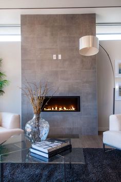 a living room with a fire place in the fireplace and two white chairs around it