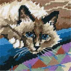 a cross stitch picture of a cat with blue eyes on a blanket, looking at the camera