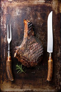 a piece of meat sitting on top of a table next to two knives