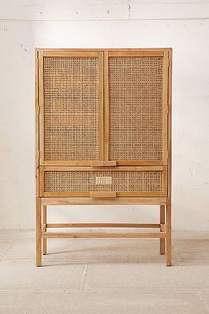 a wooden cabinet with wicker doors on the top and bottom, against a white wall