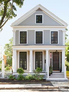 a white two story house with black shutters on the front door and porches