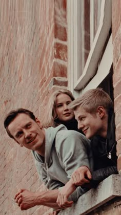 two boys and a girl are looking out the window from an old brick building with windows