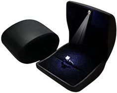 an open box with a ring in it and a light shining through the opening lid