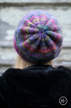 a woman wearing a multicolored knitted hat with a flower in the center