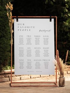 an outdoor seating chart is set up on a wooden stand with two vases next to it