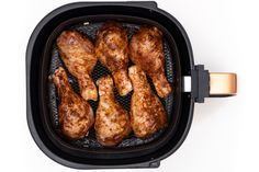 several pieces of chicken cooking in an air fryer on a white background with clippings