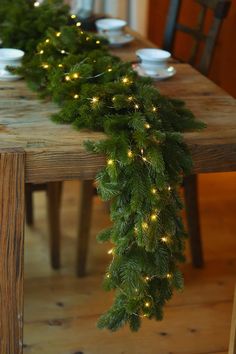 a long table is decorated with christmas lights and greenery for the holiday tablescape