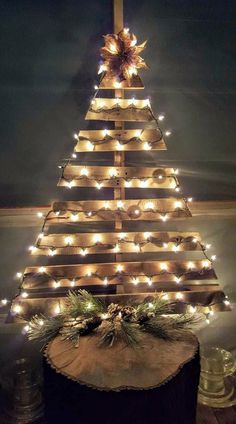 a christmas tree made out of wooden boards with lights around it and pine cones on top