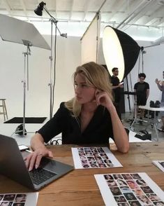 a woman sitting at a table in front of a laptop computer