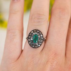 This antique Georgian ring features a .72 carat emerald and accent diamonds in two-tone 14 karat yellow gold and sterling silver. The oval cut emerald has a green-blue hue and is prong set in the center of an oval mounting. Thirty (30) accent diamonds halo the center emerald with six (6) accent diamonds decorating the shoulders of the band, set in sterling silver. From the profile, an openwork basket mounting holds the collection of gemstones finished on a polished and engraved 14 karat yellow g Oval Emerald Ring With Single Cut Diamonds, Heirloom Emerald-cut Ring With Single Cut Diamonds, Oval Green Rose Cut Diamond Rings, Heirloom Emerald Cut Ring With Single Cut Diamonds, Oval Emerald Ring With Rose Cut Diamonds, Green Oval Diamond Ring With Single Cut, Green Oval Single Cut Diamond Rings, Silver Emerald-cut Ring With Rose Cut Diamonds, Classic Oval Emerald Ring With Single Cut Diamonds