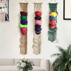 two wall hangings with hats on them in a living room next to a couch