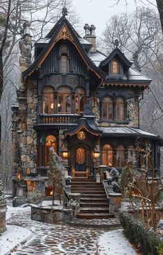 a stone and wood house surrounded by trees with snow on the ground in front of it