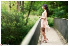 a woman standing on a bridge with trees in the background