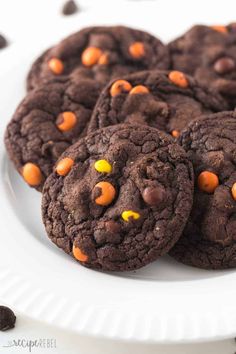 a white plate topped with chocolate cookies covered in candy corn and m & m candies