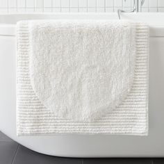 a white bath mat sitting on top of a tub next to a faucet