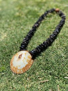 This handmade lei is a unique treasure crafted with care, featuring kukui nut shell pieces intricately woven together to create a stunning base. At its center lies a magnificent big opihi shell, sourced from the pristine shores of Hawaii, adding a touch of natural elegance and a sense of island charm. This one-of-a-kind creation is a perfect gift for any occasion, symbolizing beauty, tradition, and the spirit of aloha. Brown Shell-shaped Jewelry For Vacation, Brown Shell Jewelry For Vacation, Handmade Spiritual Shell, Artisan Handmade Shell Craft, Handmade Brown Shell-shaped Necklace, Handmade Brown Shell Necklace, Handmade Shell Necklace, Kukui Nut Lei, Kukui Nut