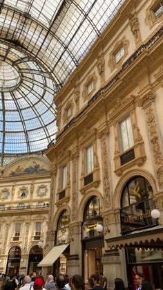 many people are walking around in an indoor shopping area with glass ceiling and high ceilings