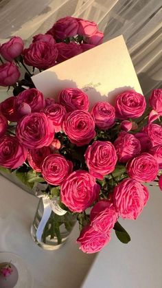 a vase filled with pink roses on top of a table next to a white plate