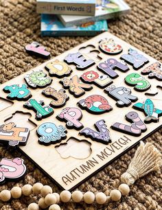 the wooden puzzles are laying on the floor next to some books and bead necklaces