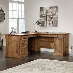 a wooden desk sitting on top of a hard wood floor next to a white rug