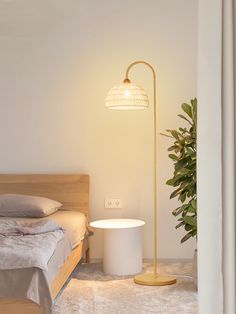 a bedroom with a bed and a lamp on the floor next to a potted plant