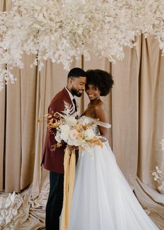 a bride and groom standing in front of flowers