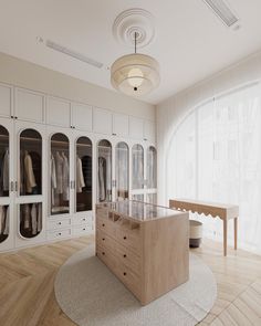 a large closet with lots of white cabinets and glass doors on the walls, along with a round rug in front of it