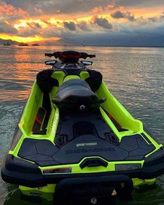 a yellow and black jet ski is in the water at sunset with clouds above it