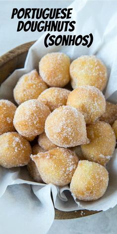 a wooden bowl filled with sugar covered doughnuts