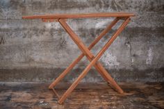 an ironing board sitting on top of a wooden table next to a concrete wall