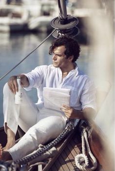 a man sitting on top of a boat holding papers