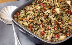 a casserole dish filled with rice, vegetables and nuts on a blue table cloth