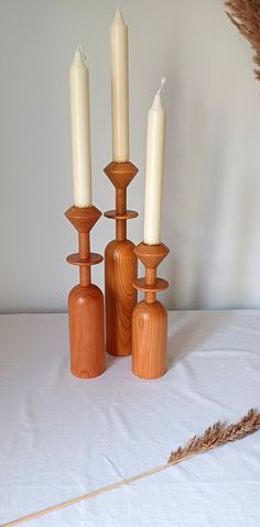 three wooden candlesticks and one is turned upside down