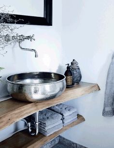 a large metal bowl sitting on top of a wooden shelf next to a bathroom sink