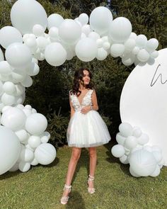 a woman standing in front of a white balloon arch