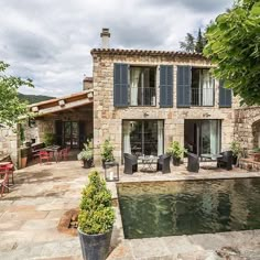 a house with a pool in front of it and patio furniture around the pool area