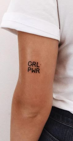 a woman's arm with the word girl pwr tattooed on her left arm