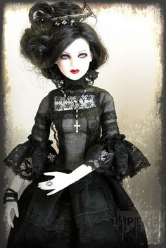 a doll dressed in black and wearing a dress with laces on it's sleeves