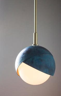 a blue and white light hanging from a ceiling fixture in a room with gray walls