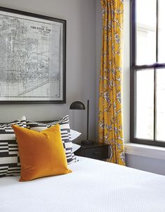 a bed with yellow and black pillows in front of a large map on the wall