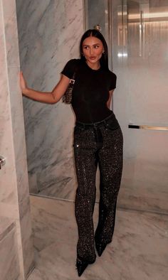 a woman in black shirt and pants standing next to a shower stall with marble walls