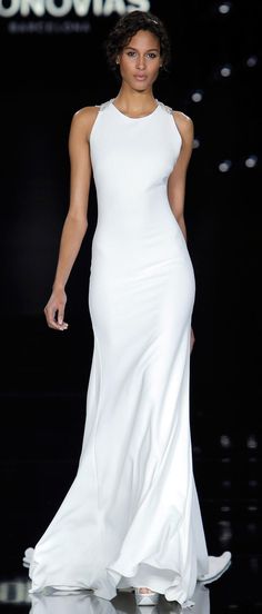 a model walks down the runway in a white gown